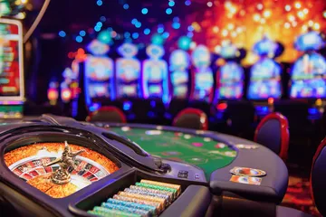 A man celebrating a winning moment on his laptop while gaming symbols float around him, capturing the excitement of 77HI games.